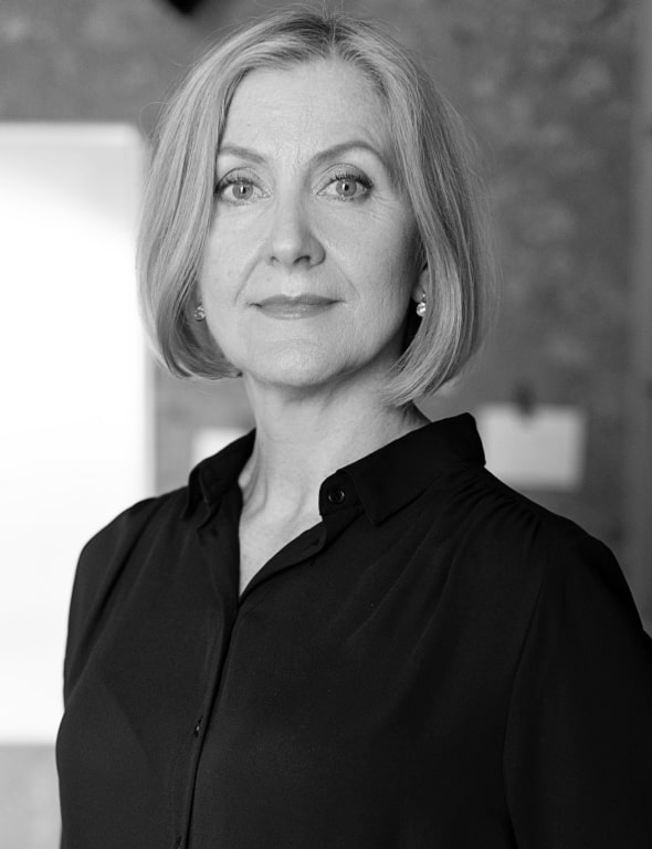 Black and white portrait of a mature woman with short blonde hair wearing a black blouse, looking directly at the camera.