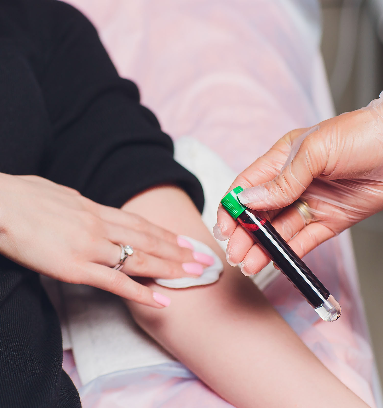 A healthcare professional takes a blood sample from a patient's finger using a lancing device.